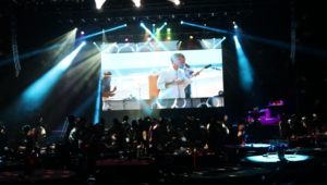 onas Brothers’ “Cake by the Ocean” music video playing on a large screen during a live video DJ performance at the Bomb Factory in Dallas, with the audience dancing and engaged.