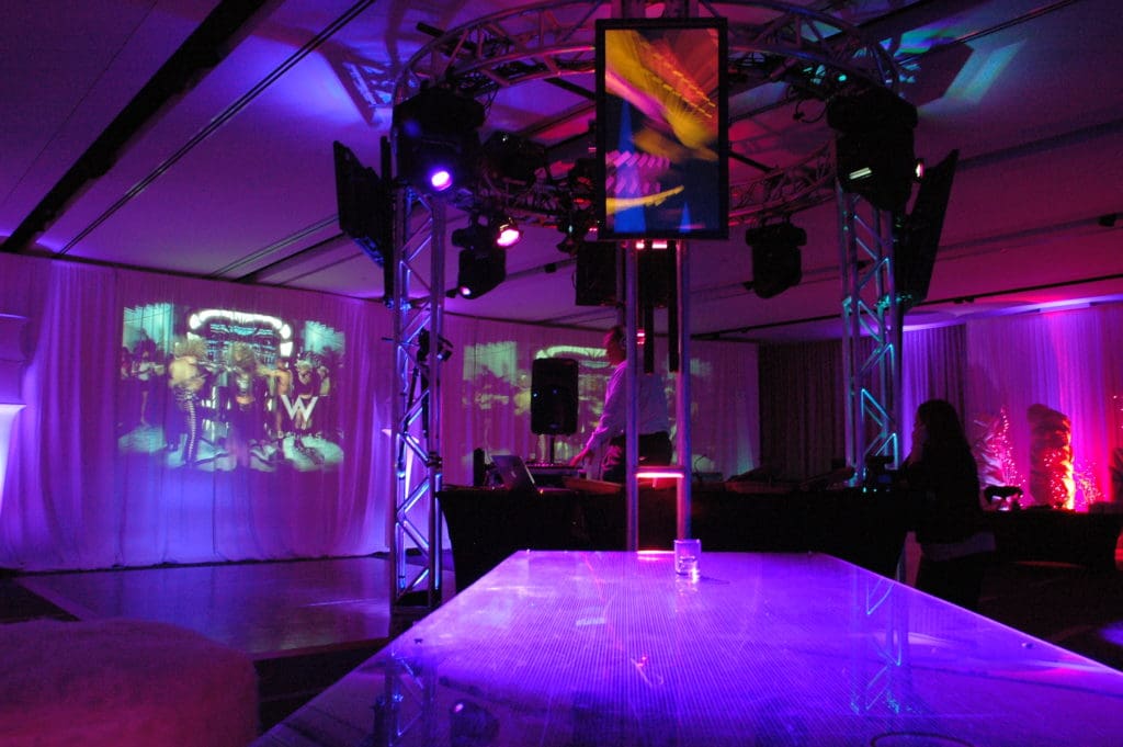 Video DJ setup with truss lighting, screens and wall projection at a W Dallas event