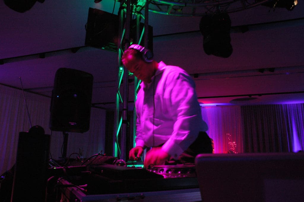 DJ mixing music on turntables under purple stage lighting