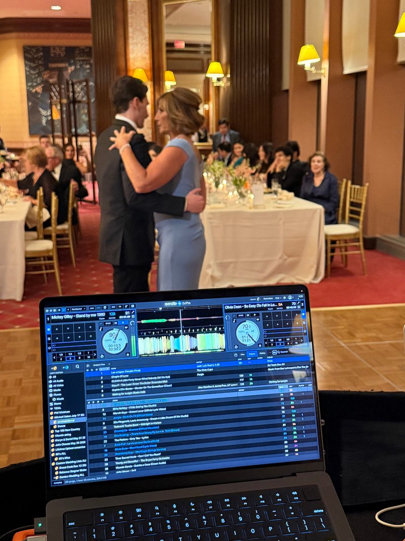 couple dancing at a wedding with DJ equipment in foreground