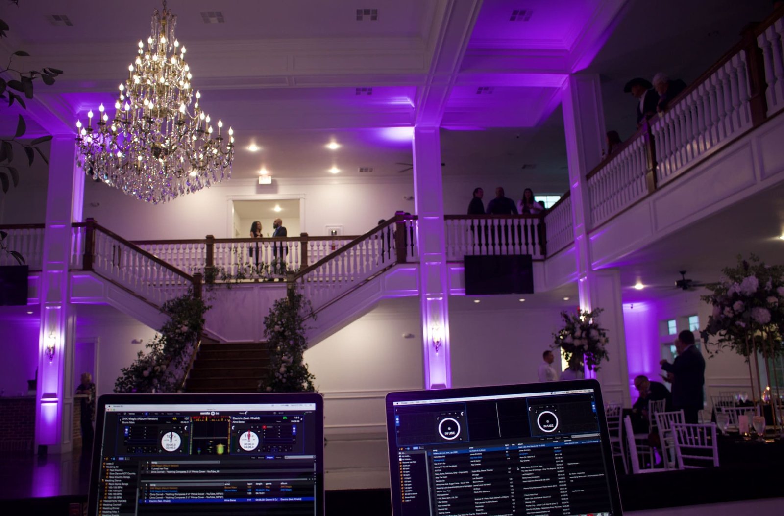 Wedding guests dancing under purple and green uplighting at The Springs in Weatherford, with the DJ booth visible in the reception ballroom.