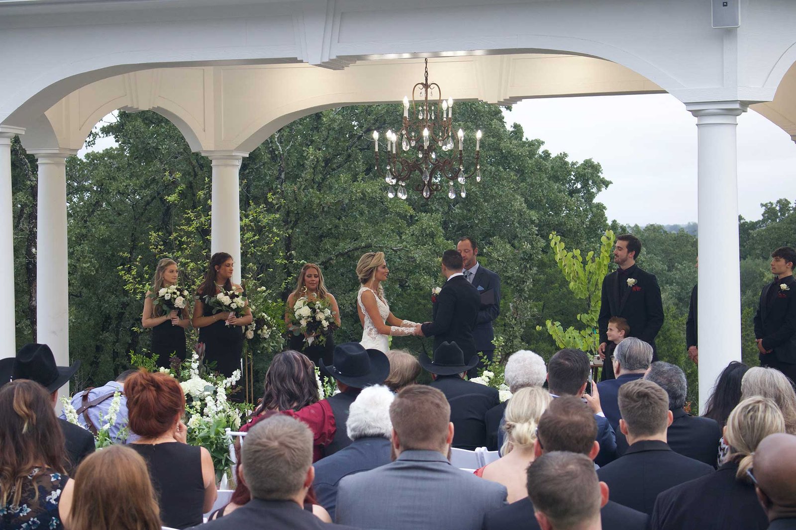 Bride and groom exchanging vows during an outdoor wedding ceremony beneath the pavilion at The Springs in Weatherford, Texas.